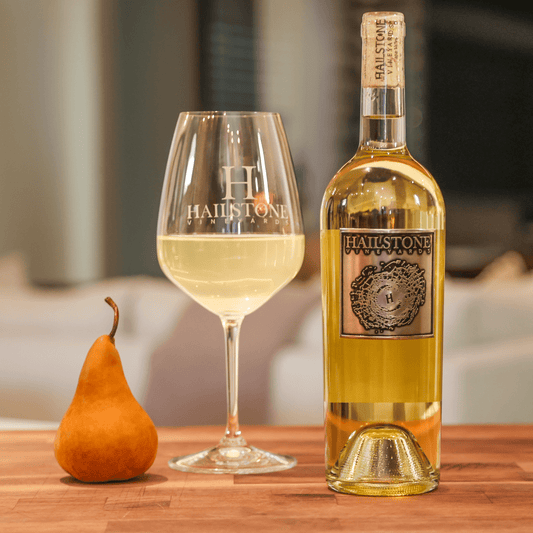 a glass full of 2021 32 Degrees Sauvignon Blanc on a Wood Table with the Bottle to the Right of it