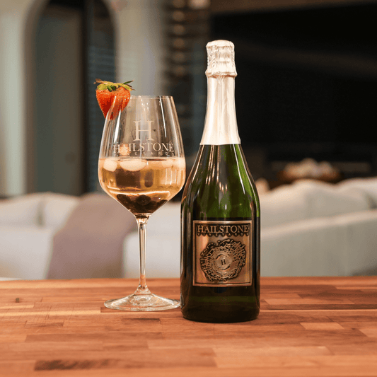 A glass full of Hailstone ICE on a Wood Table with the Bottle to the Right of it