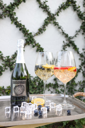 A Hailstone wine bottle with two glasses full of wine and fruit